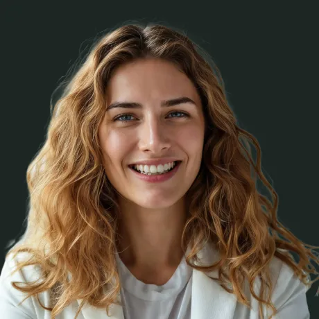 Smiling young woman with light brown curly hair wearing a white shirt and blazer against a dark background.